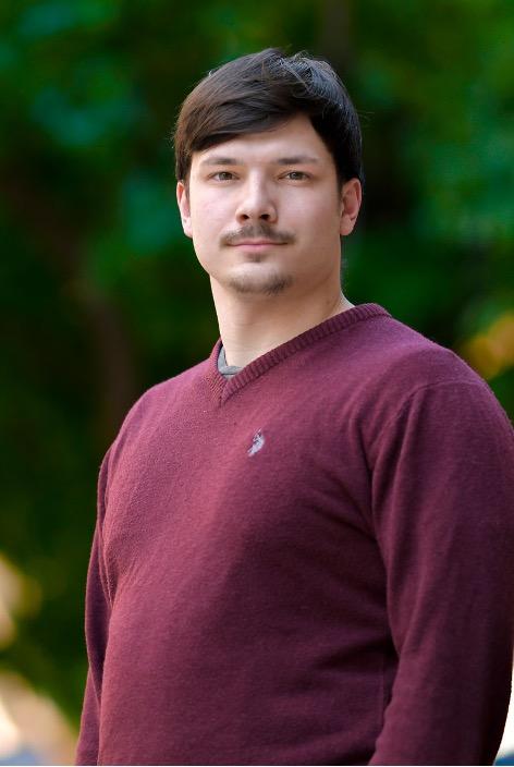 man with dark hair smiling lightly