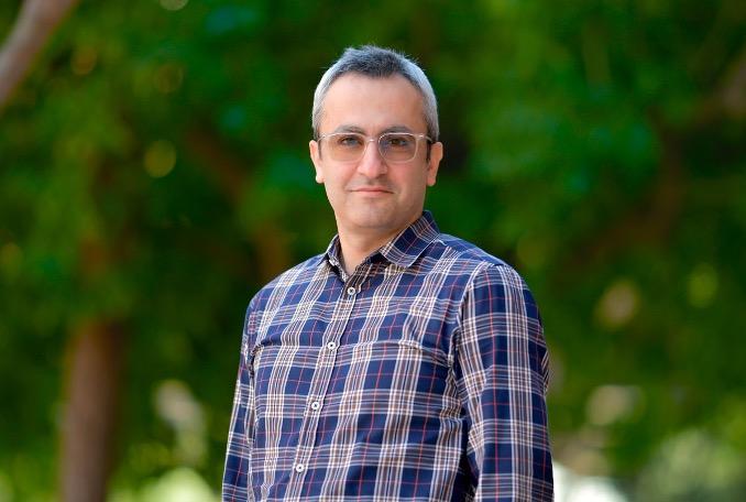 man in a plaid shirt with clear glasses on smiling