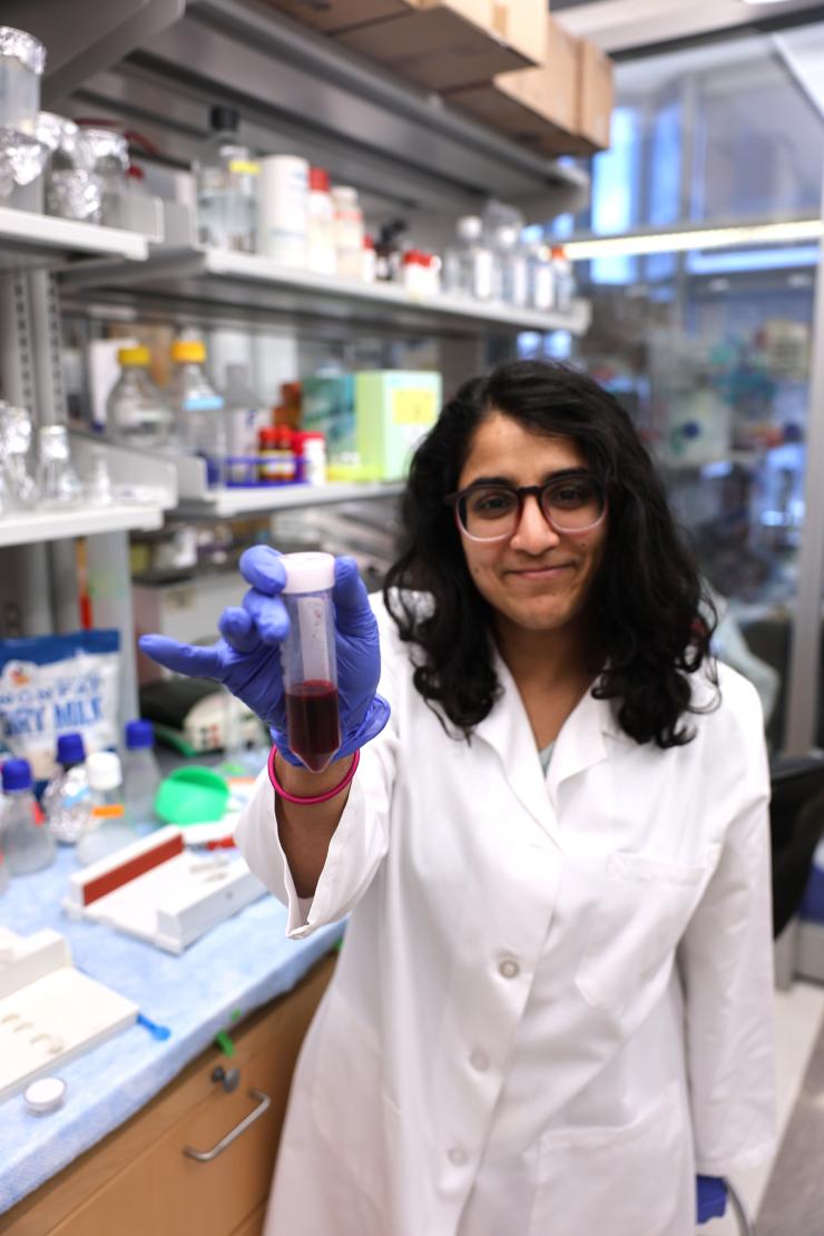 female in white coat holding testing tube
