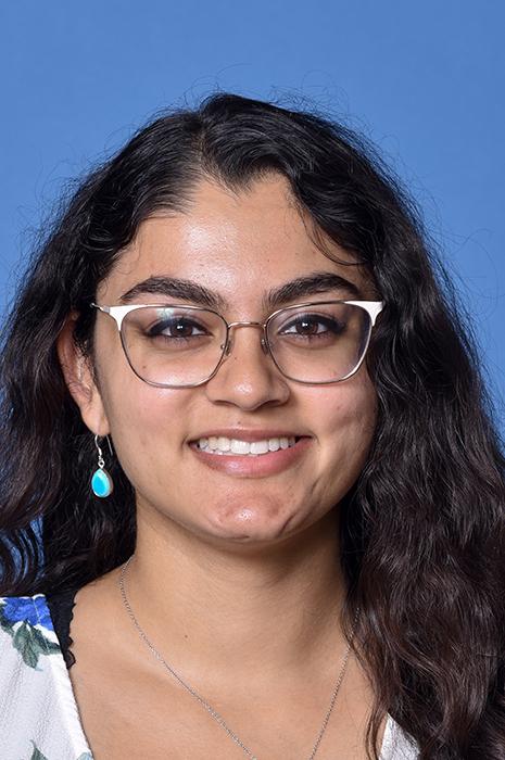 woman with dark curly hair and glasses on smiling