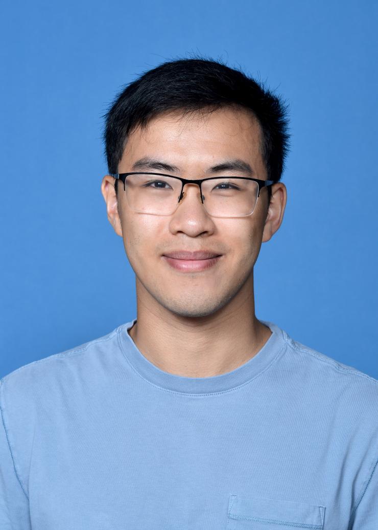 man with short dark hair and glasses on smiling lightly
