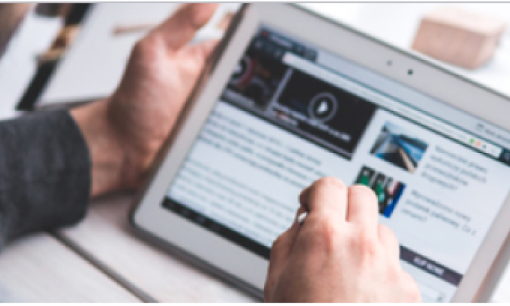 person scrolling through news site on tablet