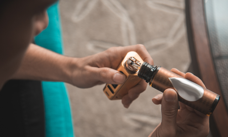 A person filling their e-cigarette with fluid.