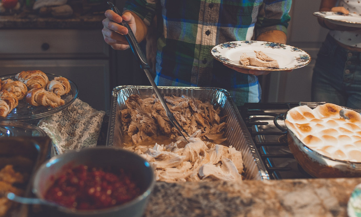 Individuals plating food during a holiday gathering.