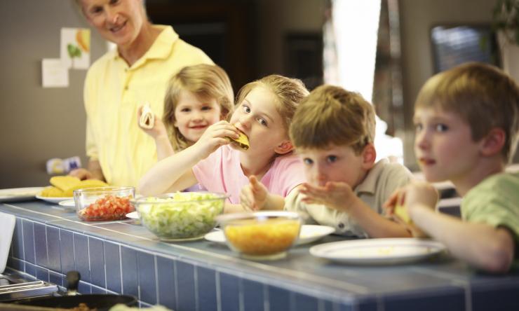 A group of children making and eating hard-shell tacos.