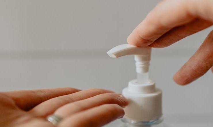 A person getting soap from a pump bottle to wash their hands.
