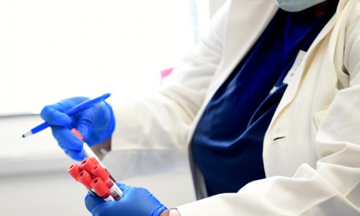 Masked doctor holding medical vials with gloved hands