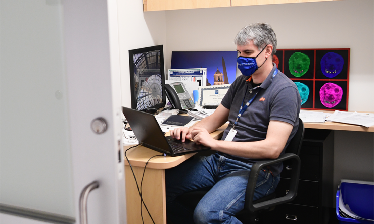 Faculty in mask at desk