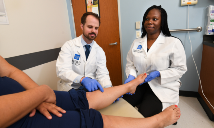 Two doctors, one male and one female, consulting with a patient about their foot.