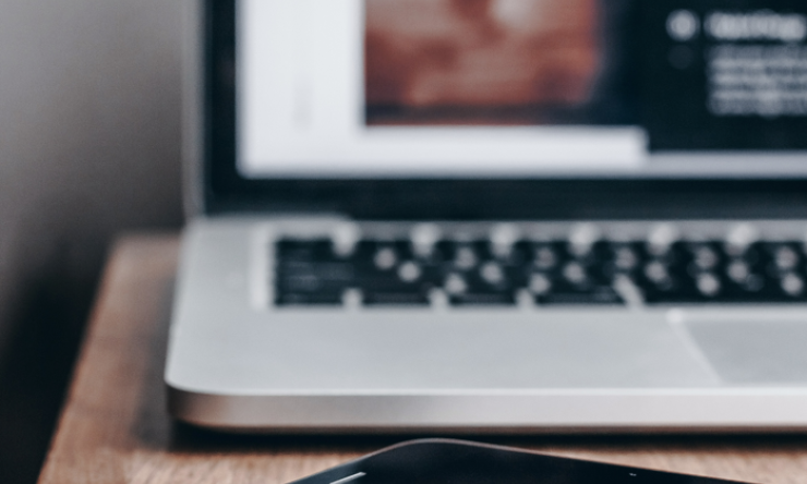 A cell phone and laptop sitting on a table, slightly out of focus