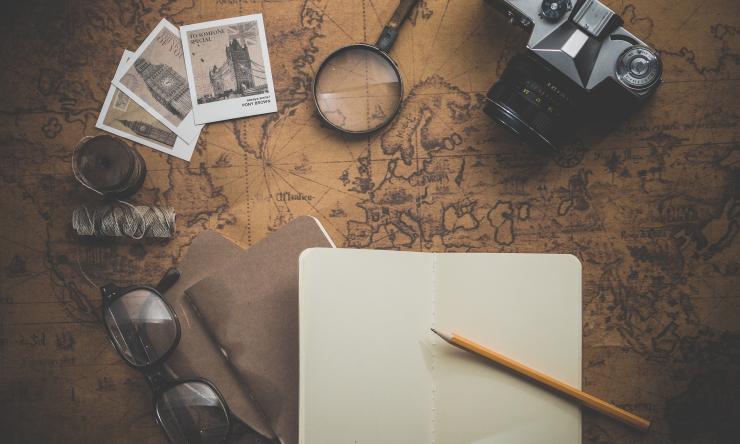 photo oa a camera, photos, glasses, notebook on a brown colored map