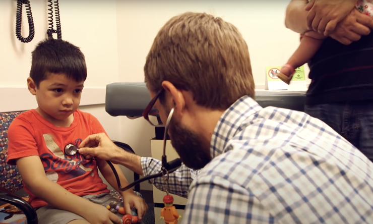 A doctor with a stethoscope listening to a child's chest