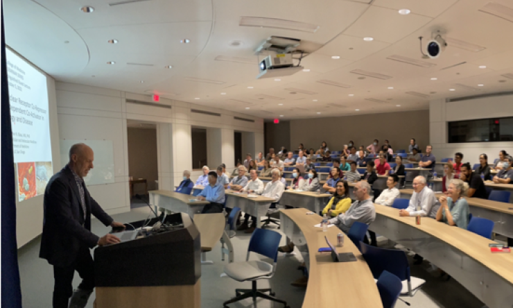 A speaker presenting in front of a crowd of students