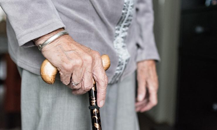 Close up photo of an elderly woman's hands holding a cane