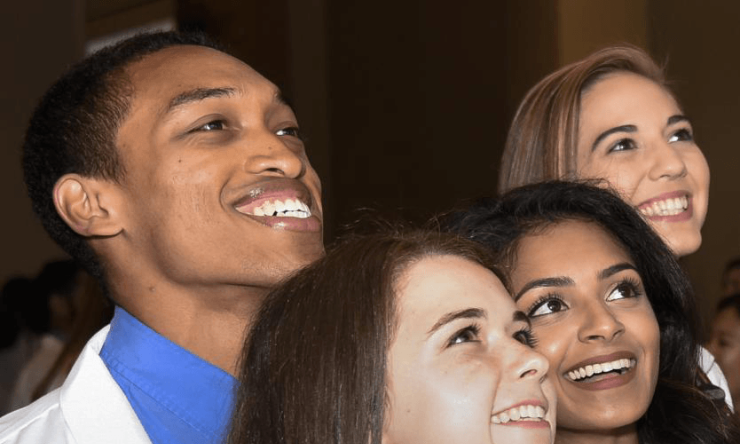 Four students looking upward and smiling