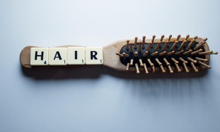 A photo of a hair brush with the word hair spelled out in scabble tiles.