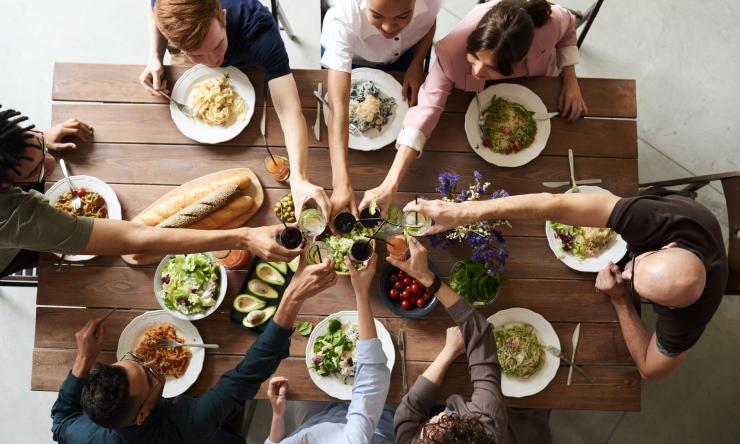 Group of friends eating dinner, toasting, shot from above. 