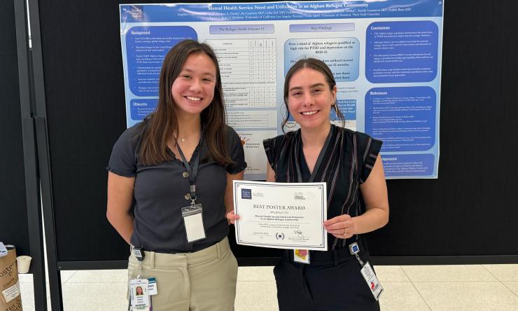 two women smiling and holding an award certificate
