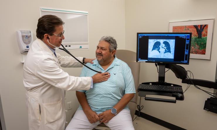 Dr. Ivan Rosas listening to a patient's chest with a stethoscope 