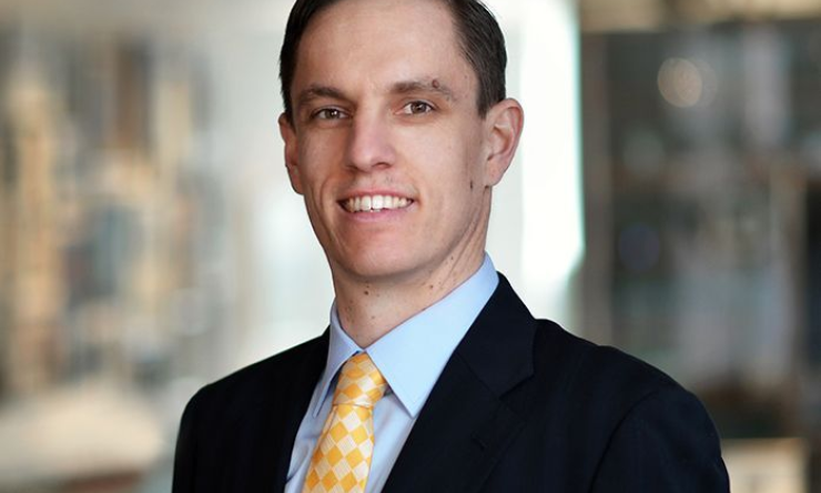 man in dark blazer and yellow tie smiling