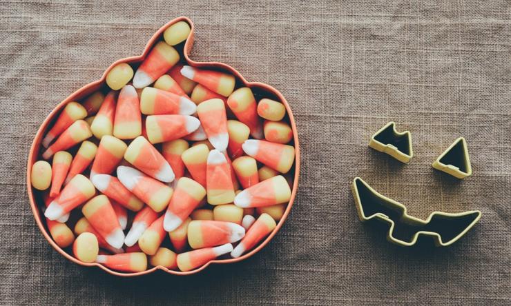 Photo of candy corn in a bowl shaped like an pumpkin. 