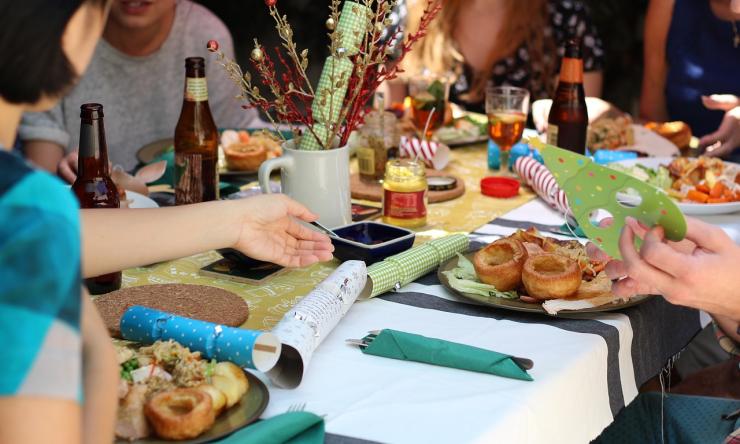 Photo of a dining table with plates / food and Christmas favors, showing friends gathered to party. 