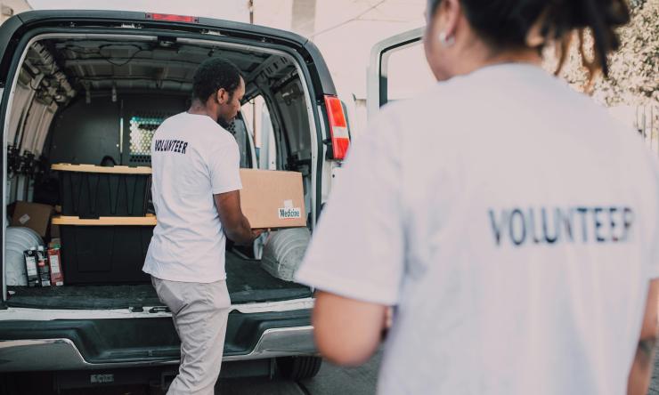 Photograph of volunteers loading a van with boxes of donations. 