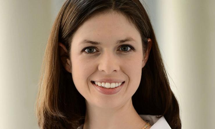woman with shoulder length brown hair in a whote doctor coat smiling