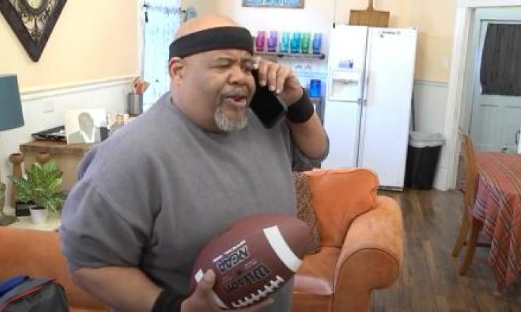 a man holding a football and talking on the phone in his home