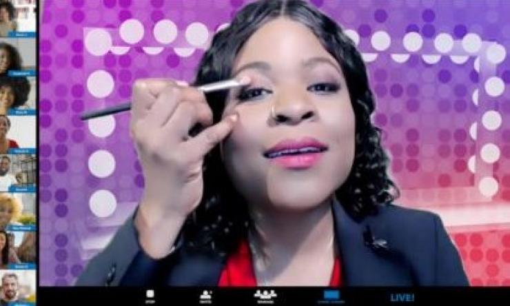 a woman doing her makeup with a colorful background behind her