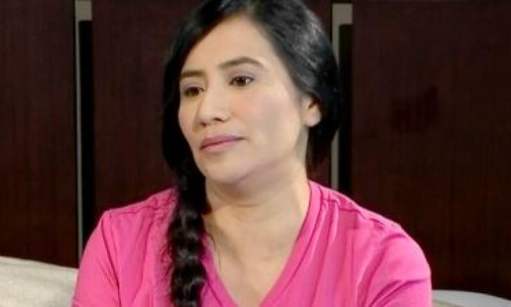 woman in a pink shirt with a side braid smirking