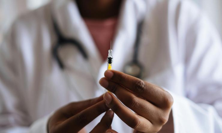Photo of a doctor holding a syringe to vaccinate a patient. 