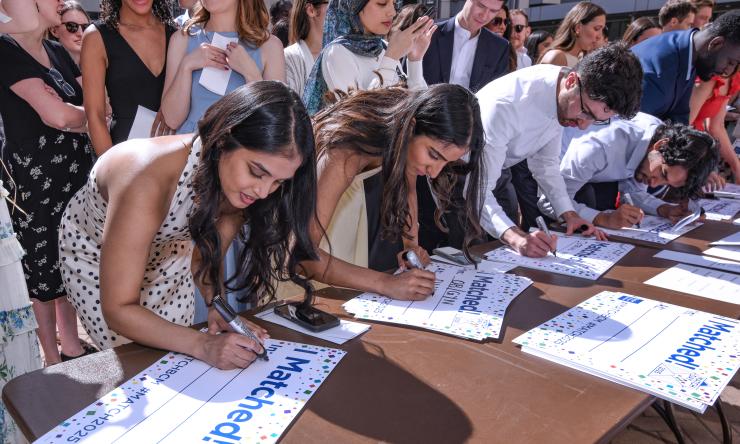 A group of students leaning over a table, signing their name on posters reading "I Matched."