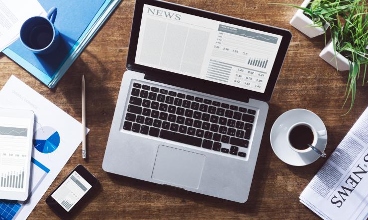 a laptop sitting on a desk with news on the screen