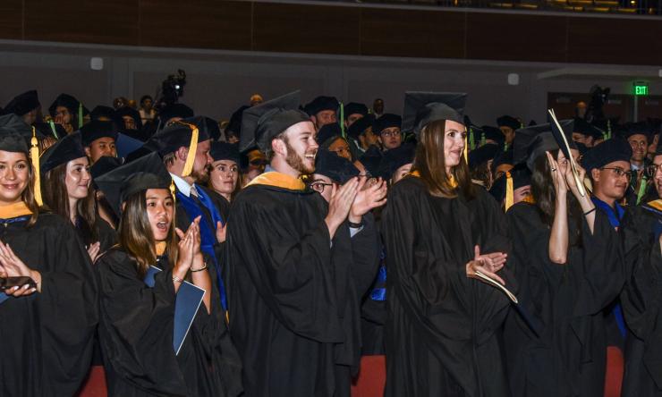 A photo of graduates clapping during their commencement ceremony. 