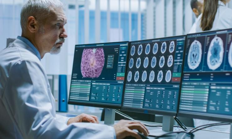 a doctor looking at computer screen with brain scans