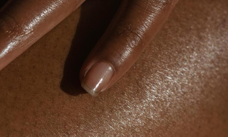 Close up photo of a hand touching their skin to represent skin health.