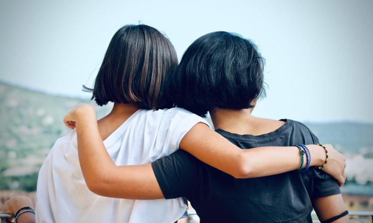 A photo taken from behind of two girls hugging, supporting each other during a difficult time. 