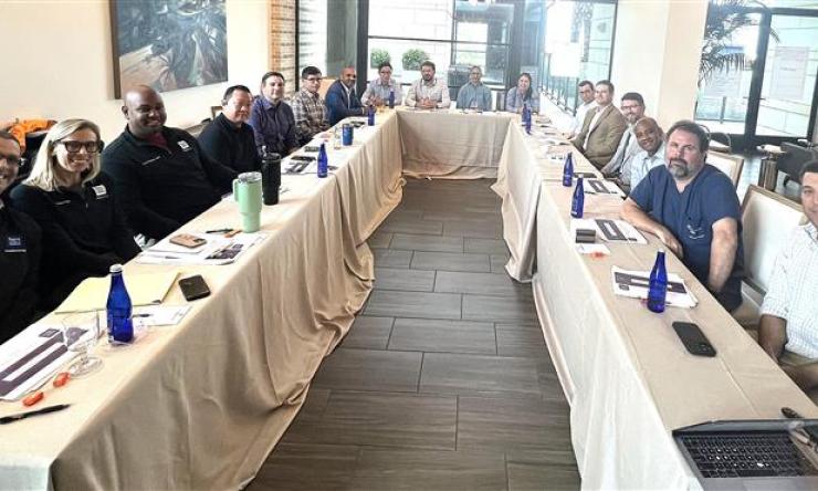 a large group of people sitting at a table smiling