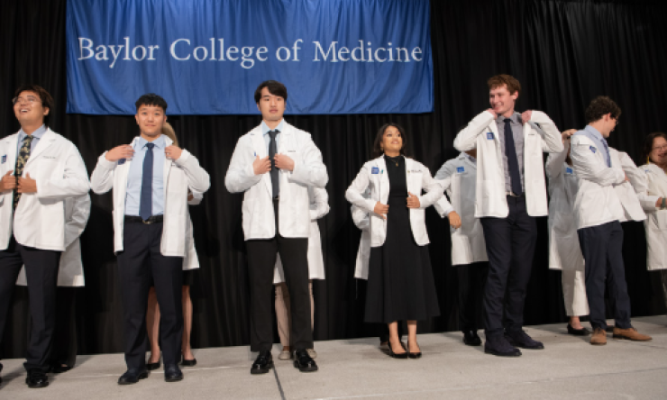 a group of people putting on their white doctor coat for the first time on a stage