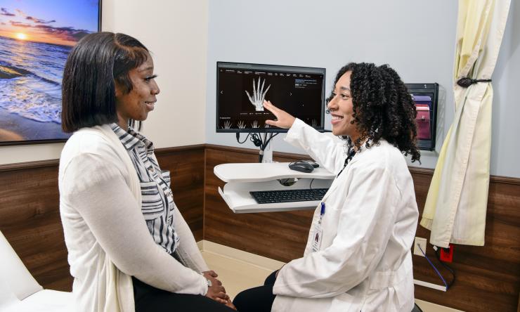 a patient looking at her doctor, who is pointing to a screen