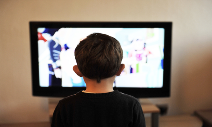 A child seen from behind watching a television.