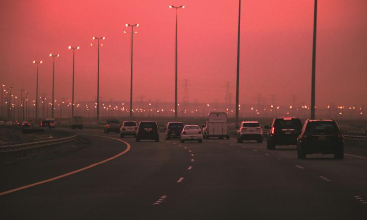 Cars driving on highway with hazy polluted skies in background