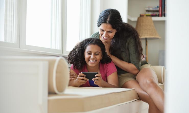 child and her mom looking at a phone together