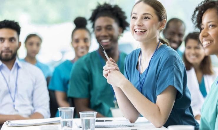 Photo of students with a female leaning on a table smiling