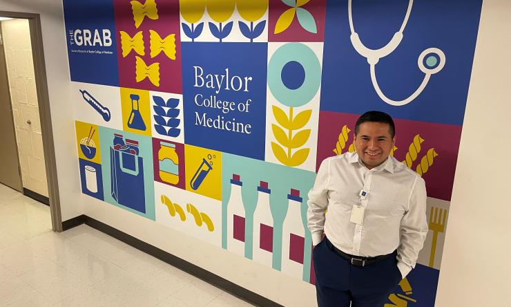 Alex Alanis stands infront of the wall decal outside the GRAB