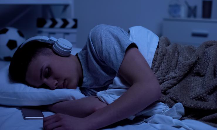 a teenager sleeping with headphones on