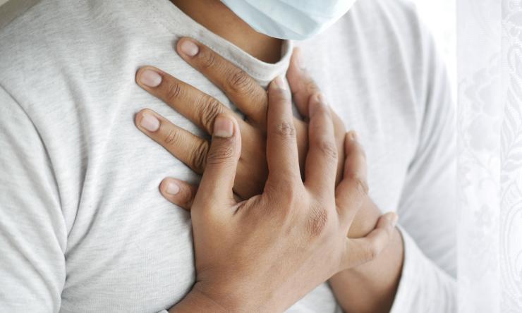 Photo of a man clutching his chest to indicate he is having trouble breathing.