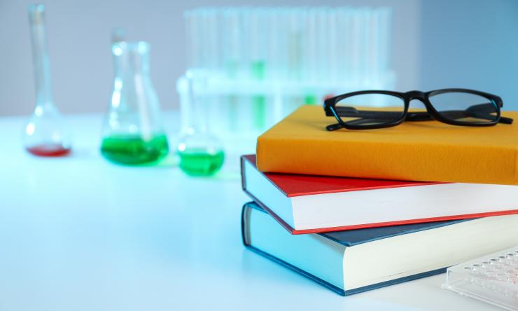 glasses on a stack of books with test tubes in the background
