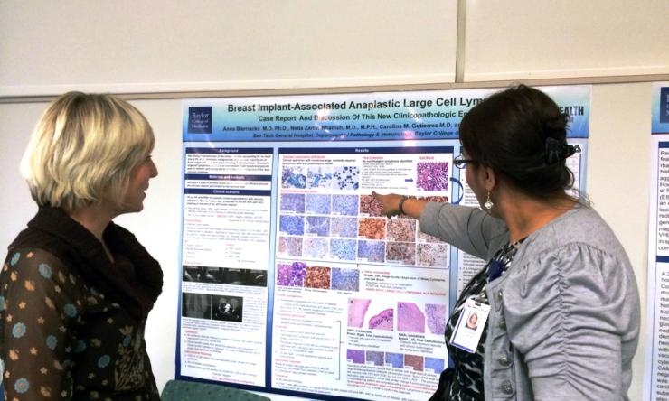 Pathology resident receiving feedback from faculty about her poster presentation.